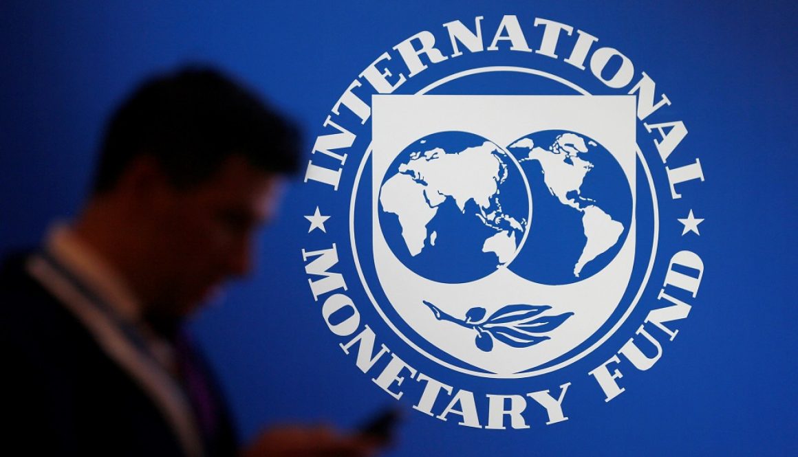 A participant stands near a logo of IMF at the International Monetary Fund - World Bank Annual Meeting 2018 in Nusa Dua