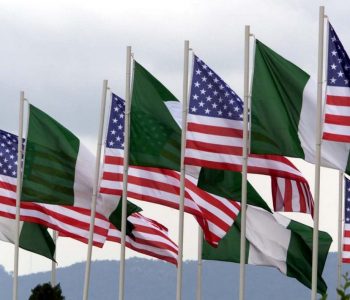 AMERICAN AND NIGERIAN FLAGS FLY NEXT TO EACH OTHER.