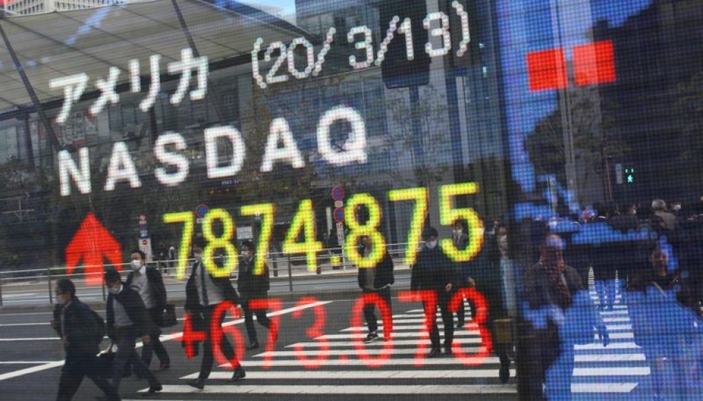 FILE PHOTO: People wear protective face masks as they are reflected in a stock quotation board outside a brokerage in Tokyo